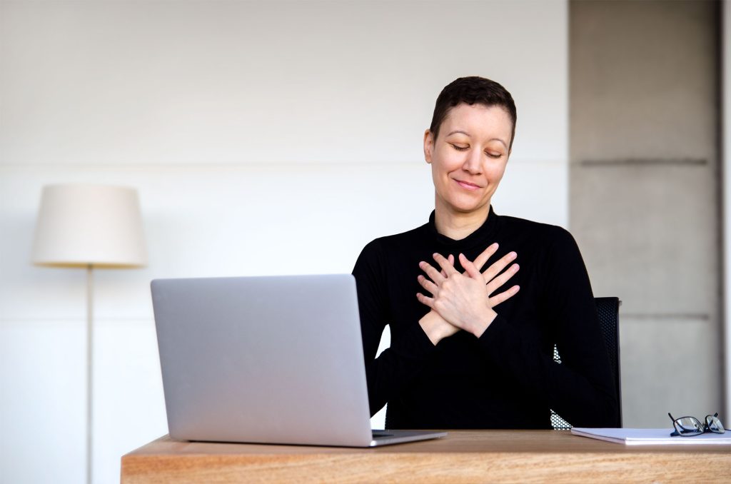 Therapist website copywriter Kat Love at their laptop with hands over heart sharing black friday deals for therapists