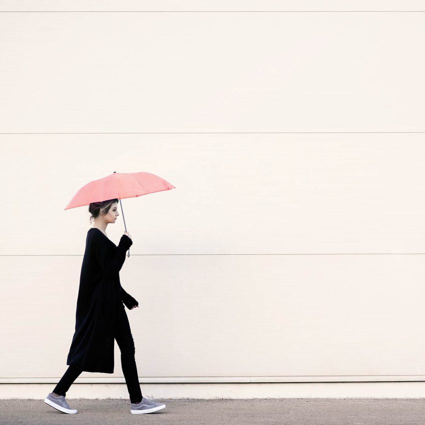 Therapist with umbrella walking away from challenges they have when writing their therapist website about page
